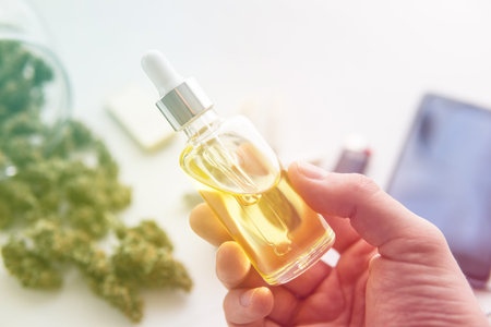 CBD cannabis OIL on white background, bottle of oil Cannabis in pipette in hand, hemp product,...