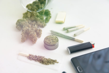 Cannabis buds on black table, close up, joint with marijuana, grinder with fresh weed , light leaks...