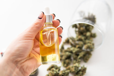 medical hemp concept, oil Cannabis CBD in pipette women hand, marijuana extract on white background,...
