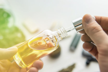 bottle of oil Cannabis in pipette in hand, close up, hemp product, CBD cannabis OIL on white background, medical marijuana concept, light leaks color tonesの写真素材