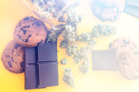 Treatment of medical marijuana for use in food, yellow background. Cannabis CBD herb Chocolate and...