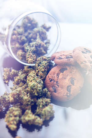 Concept of cooking with cannabis herb. Cookies with cannabis and buds of marijuana on the table. Treatment of medical marijuana for use in food, On a black background. Vertical shotの写真素材