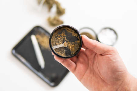 The pot leaves on buds THC CBD. Close up vertical shot. Grinder and cannabis weed bud. Marijuana nature bud. White background. Kief in grinder. Indica Sativa medical health.の写真素材