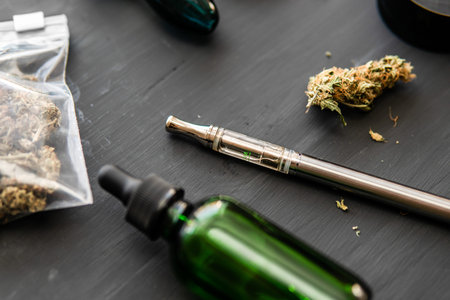 Electronic marijuana vaporizer Cannabis buds weed on black wood
