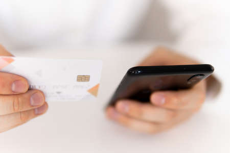 Closeup of young man making man hands using smartphone and holding credit card with social Online shopping concept in morning light. Payment online shopping smartphone at working place.の写真素材