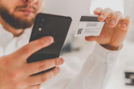Online shopping concept in morning light. Businessman hands using smartphone and holding credit card with social Close up hands holding credit card and using mobile smart phoneの写真素材