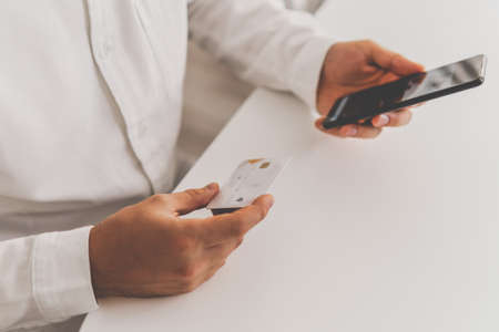 using smart phone for online shopping. credit card and Businessman hands using Online shopping concept in morning light. smartphone and holding credit card with social Online payment,の写真素材