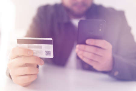hand credit card for shopping online. Web shopping. Buying online with a credit card and smart phone sitting home with a blurred background. payment online shopping smartphone at working place.の写真素材