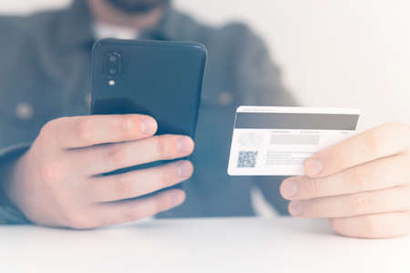 Buying online with a credit card and smart phone sitting home with a blurred background. payment online shopping smartphone at working place. hand credit card for shopping online. Web shopping.の写真素材
