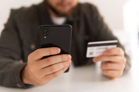 Buying online with a credit card and smart phone sitting home with a blurred background. hand credit card for shopping online. Web shopping. payment online shopping smartphone at working place.の写真素材