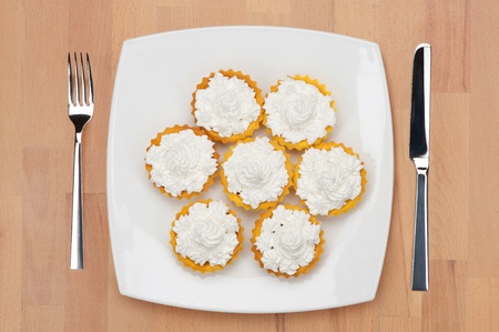 A plateful of tart shells filled with cheese, with fork and knife on a wooden table.の写真素材