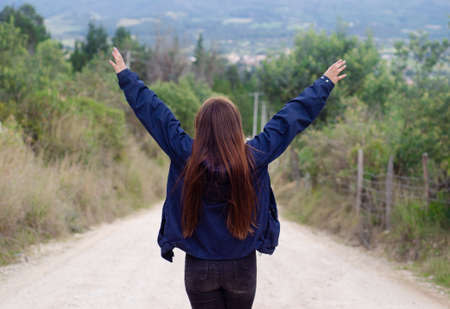 girl from behind enjoys nature on the way to the mountainの写真素材