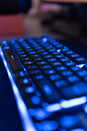 close up of a computer keyboard with blue light in the background.