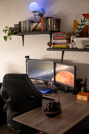 Home office workspace with computer, books, coffee cup, lamp and other itemsの写真素材