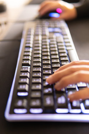 Close-up of female hands typing on computer keyboard in office.の写真素材