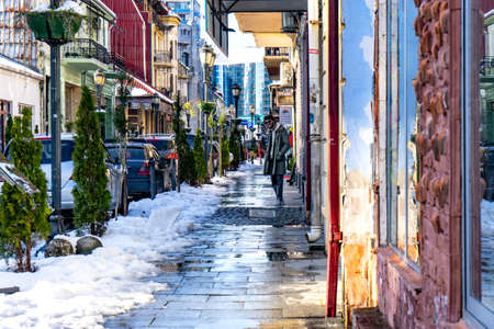 Batumi, Adjara, Georgia - 14.03.2020: unidentified young man in the  winter with snow in old quarter street with old soviet-style house residence in Batumi, Georgiaのeditorial素材