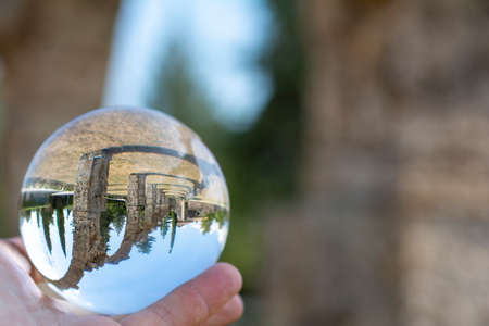 Italian summer landscape, seen through a small crystal ball, hand of man holding the lensball, ancient religious constructionsの写真素材