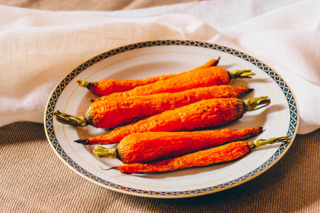 Baked carrots in a plate on a linen tablecloth. Selective focus.の写真素材
