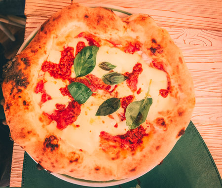 Pizza with mozzarella cheese and basil on a wooden tableの写真素材