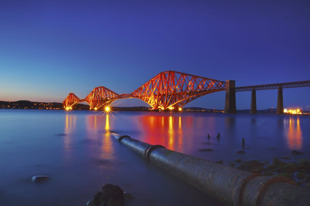 The Forth Rail Bridge crossing between Fife and Edinburgh, Scotland. Rusty iron pipe disappearing in...