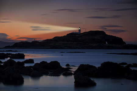 Lighthouse on Fidra island at astonishing sunset on vibrant sky background with light beam. Dirleton, Scotlandの写真素材