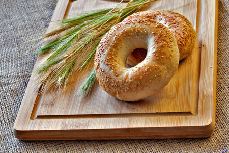 Two bagels on bread board with wheat corns on old sack cloth. Still life