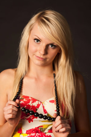 Beautiful young blonde girl with long hair posing in studio against dark backgroundの写真素材