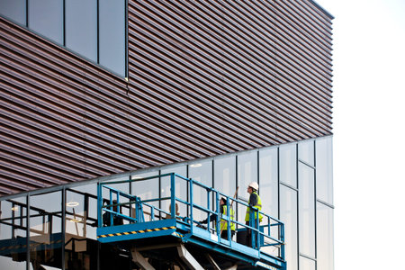 Builder on a Scissor Lift Platform at a construction site. Men at work