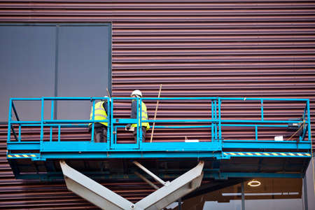 Builder on a Scissor Lift Platform at a construction site. Men at workの写真素材