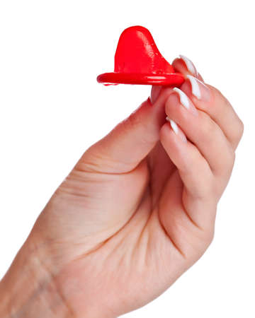 Closeup of a female hand holding red condom isolated on whiteの写真素材