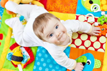 Closeup of happy six months baby boy crawling on colorful playmat