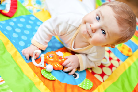 Closeup of happy six months baby boy crawling on colorful playmatの写真素材