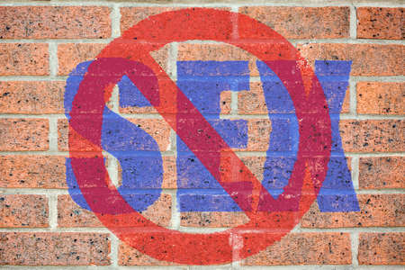 "No sex" sign on red brickwall surface as a concept of homophobia or abstinenceの写真素材