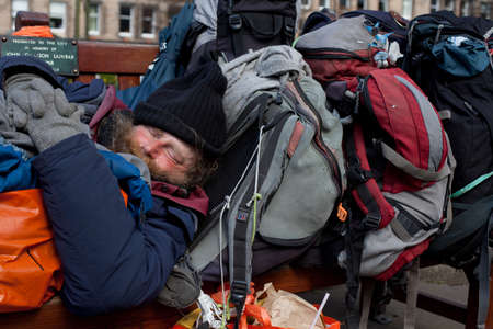 EDINBURGH, SCOTLAND - APRIL 15, 2014: Unidentified local homeless bearded man sleeps on a bench in Edinburgh on London road. This man lived on this bench during several months and never seen away. Soon after this he disappearedのeditorial素材