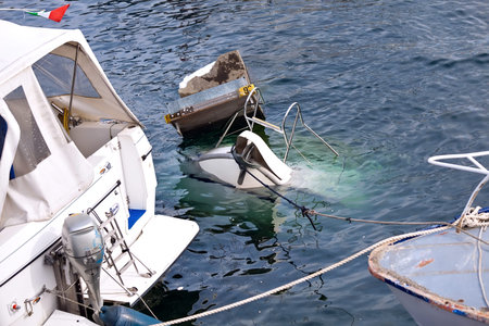 VERBANIA, LAGO MAGGIORE, ITALY - OCTOBER 12, 2013: Overnight thunderstorm destroys town's marine piers with luxury yahts and motorboats. Rescue forces working on lifting damaged boats up from the water of Lago Maggiore lake.のeditorial素材