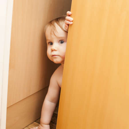 Curious cute baby toddler boy looking through ajar doorの写真素材