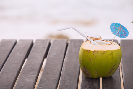 Coconut water drink served in coconut with drinking straw on the beach