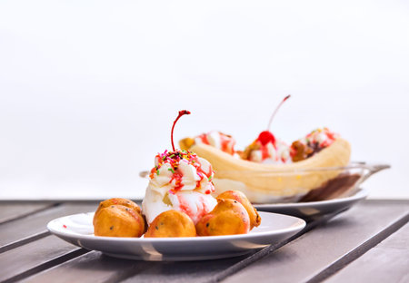 Vanilla ice cream with whipped cream and banana filled profiteroles decorated with cherry