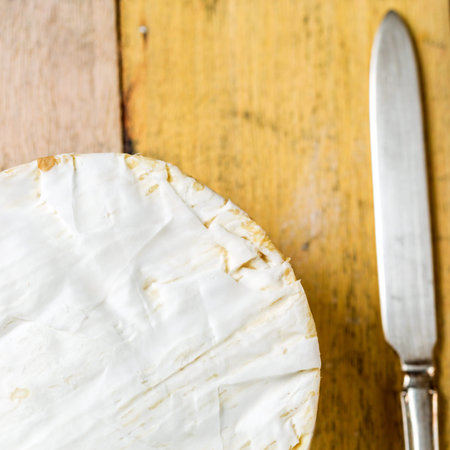 Camembert cheese and vintage knife on wooden table, top viewの写真素材