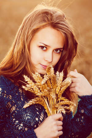 Closeup of young beautiful woman in golden wheat fieldの写真素材