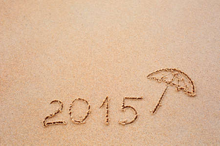 Inscription of the year 2015 written in the wet yellow beach sand. Concept of celebrating the New Year at some exotic placeの写真素材