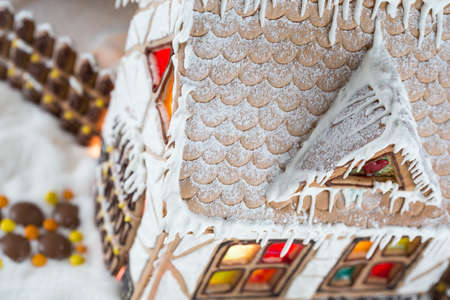 Decorative gingerbread house with lights inside on black background. Rural Christmas night sceneの写真素材