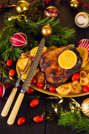 Christmas roast duck served with potatoes, orange and tomatoes on wooden festive decorated tableの写真素材