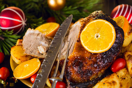 Christmas roast duck served with potatoes, orange and tomatoes on wooden festive decorated tableの写真素材