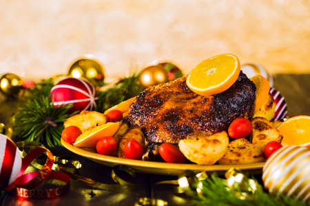 Christmas roast duck served with potatoes, orange and tomatoes on wooden festive decorated tableの写真素材