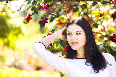 Young beautiful woman with long straight dark hair posing in spring garden