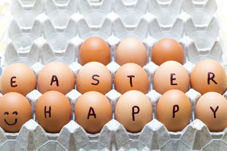 Happy Easter inscription on raw eggs in carton tray.