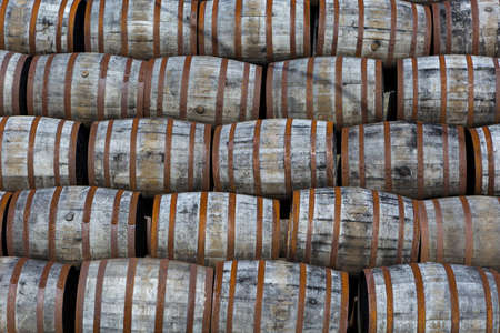 Stacked pile of old wooden barrels and casks at whisky distillery in Scotland.の写真素材