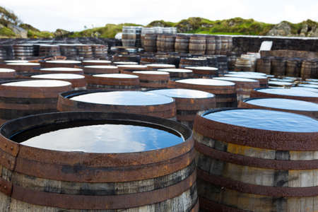 Old wooden barrels and casks stand under open sky maturing Scotch single malt Scotch at whisky distillery in Scotland.の写真素材