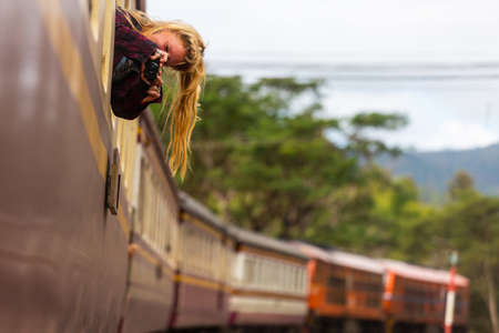 Backpacker hippie girl looks through the train car window.のeditorial素材